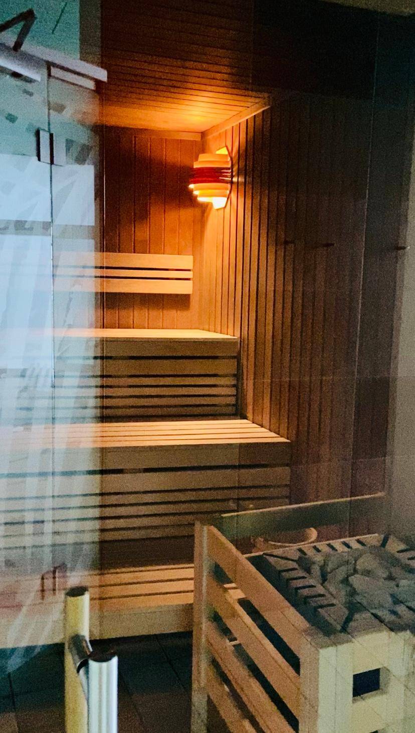 Gemütliche Holzsauna mit mehrstufigen Bänken und traditionellem Saunaofen für Entspannung.