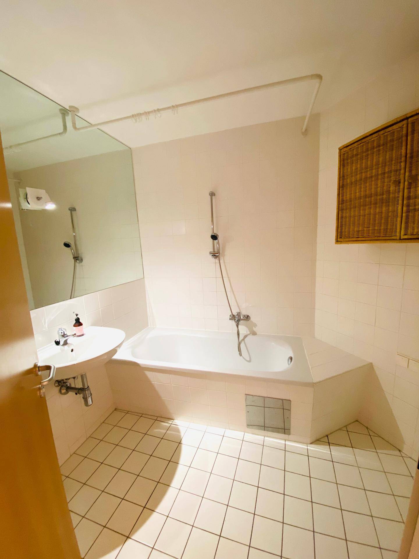 Funktionales Badezimmer mit Badewanne, Waschbecken und hellen Fliesen, in gutem Zustand.