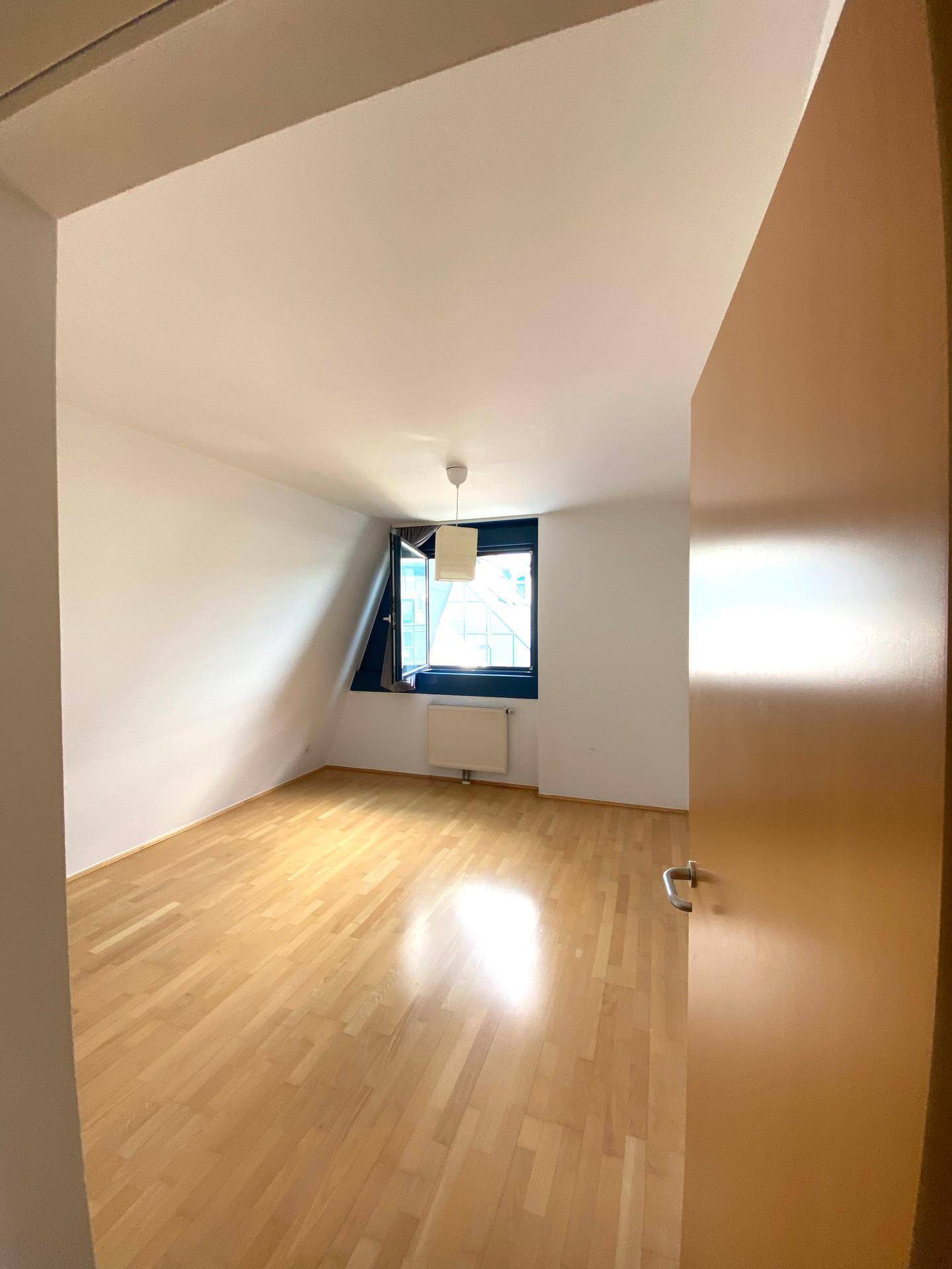 Ruhiges Schlafzimmer mit Holzboden und einem Fenster, das viel Tageslicht hereinlässt.