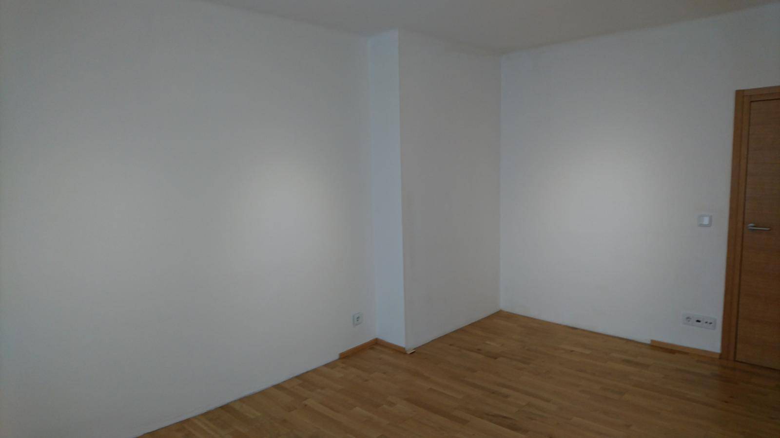 Leeres Zimmer mit weißen Wänden und Parkettboden, bereit zur individuellen Gestaltung.