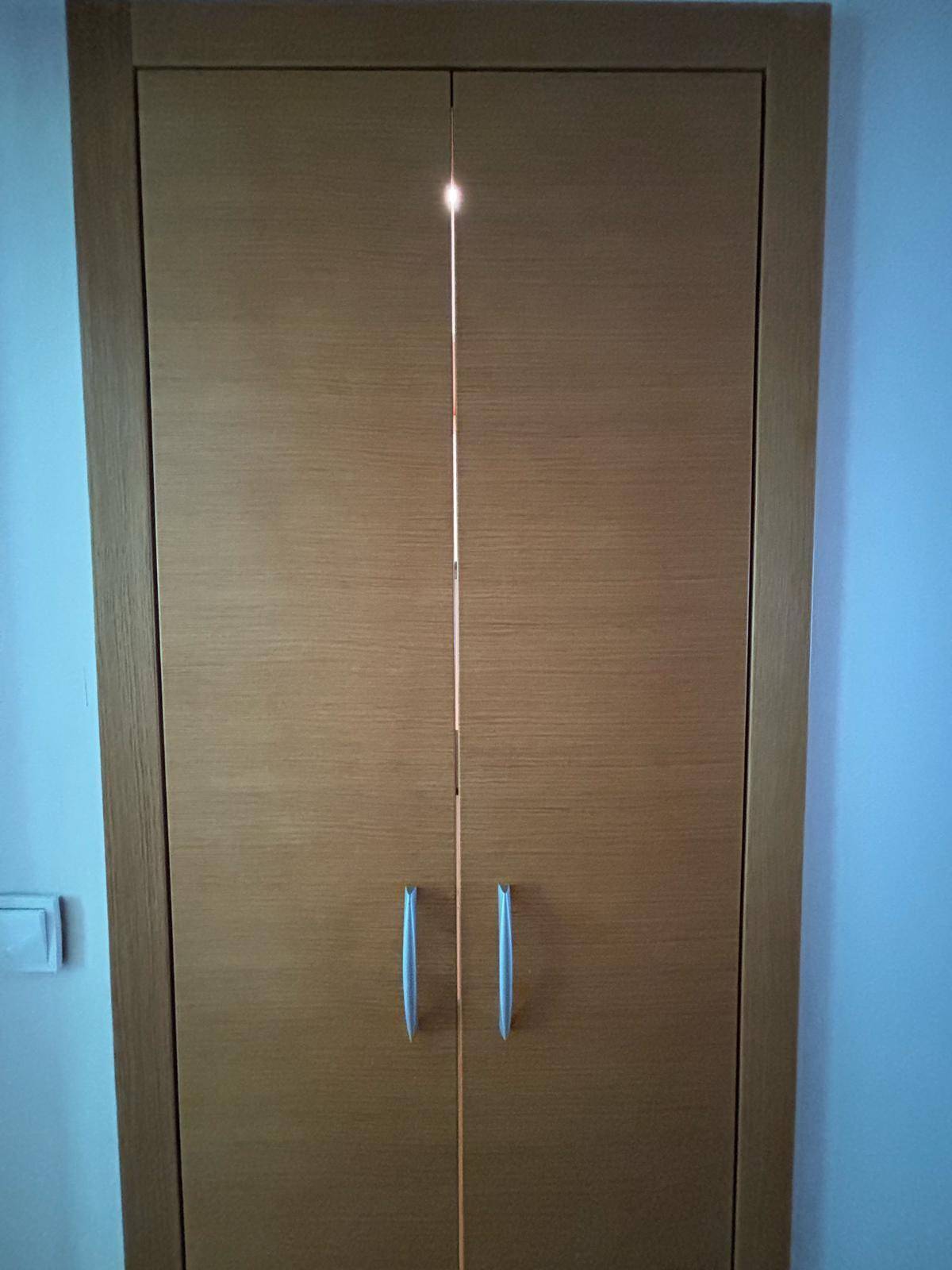 Eingebauter Wandschrank mit Holztüren und Metallgriffen, ideal für Stauraum.