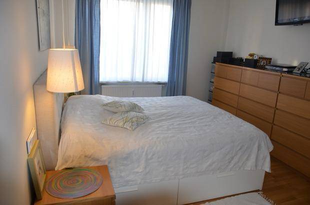 Gemütliches Schlafzimmer mit Doppelbett, Holzkommode und blauen Vorhängen.
