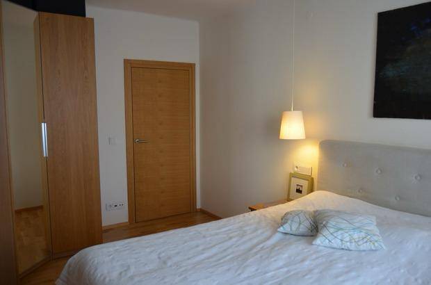Schlafzimmer mit Doppelbett, Kleiderschrank und Holztür, hell und einladend.