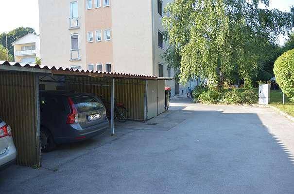 Überdachte Parkplätze für Fahrzeuge vor einem Mehrfamilienhaus.