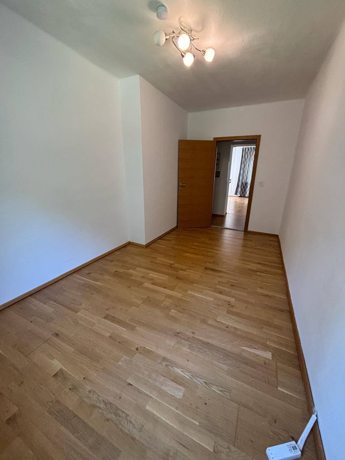 Helles Zimmer mit Parkettboden und Holztür, ideal als Schlaf- oder Arbeitszimmer.