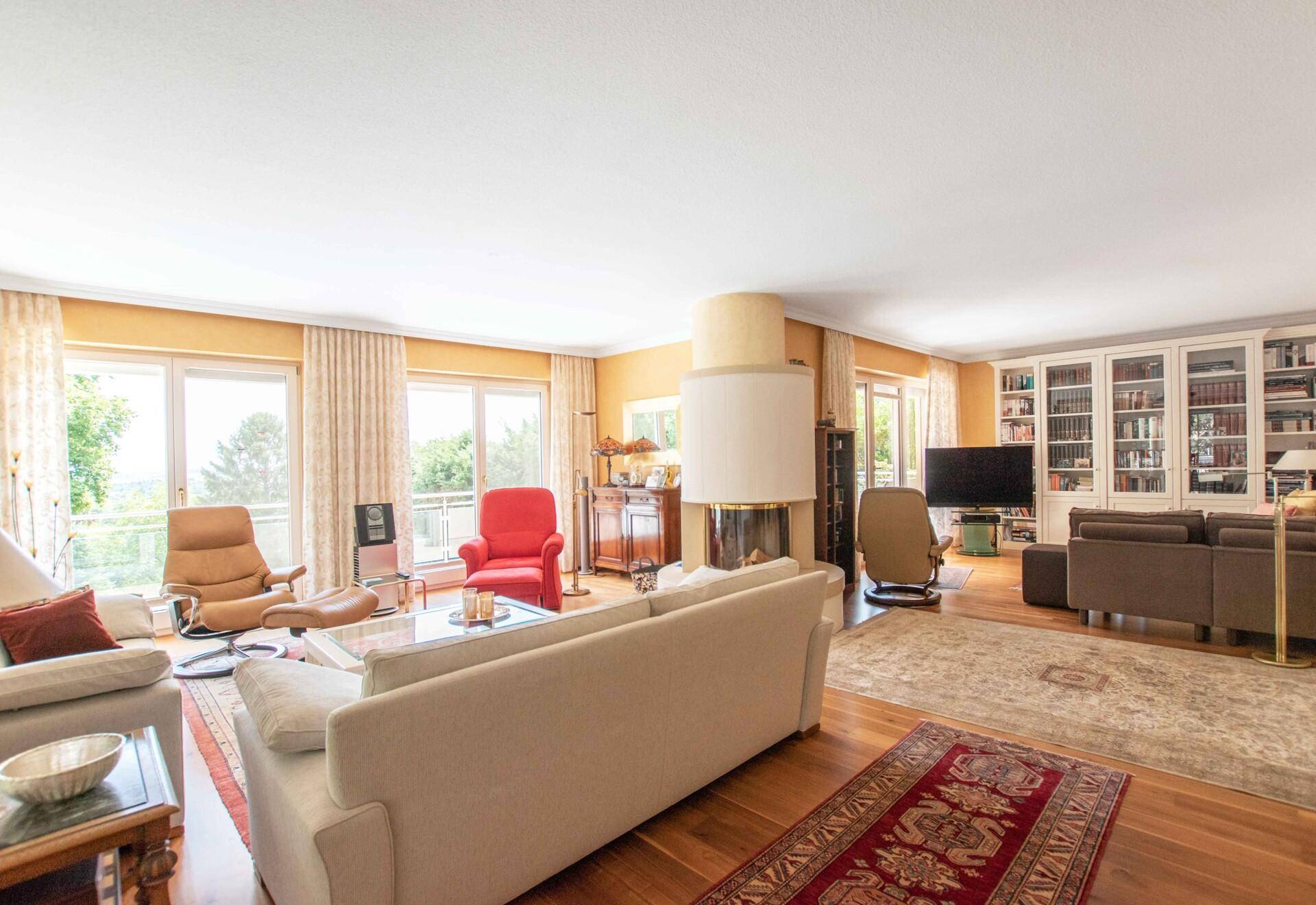 Helles Wohnzimmer mit integriertem Bücherregal, Kamin und weitem Blick ins Grüne.