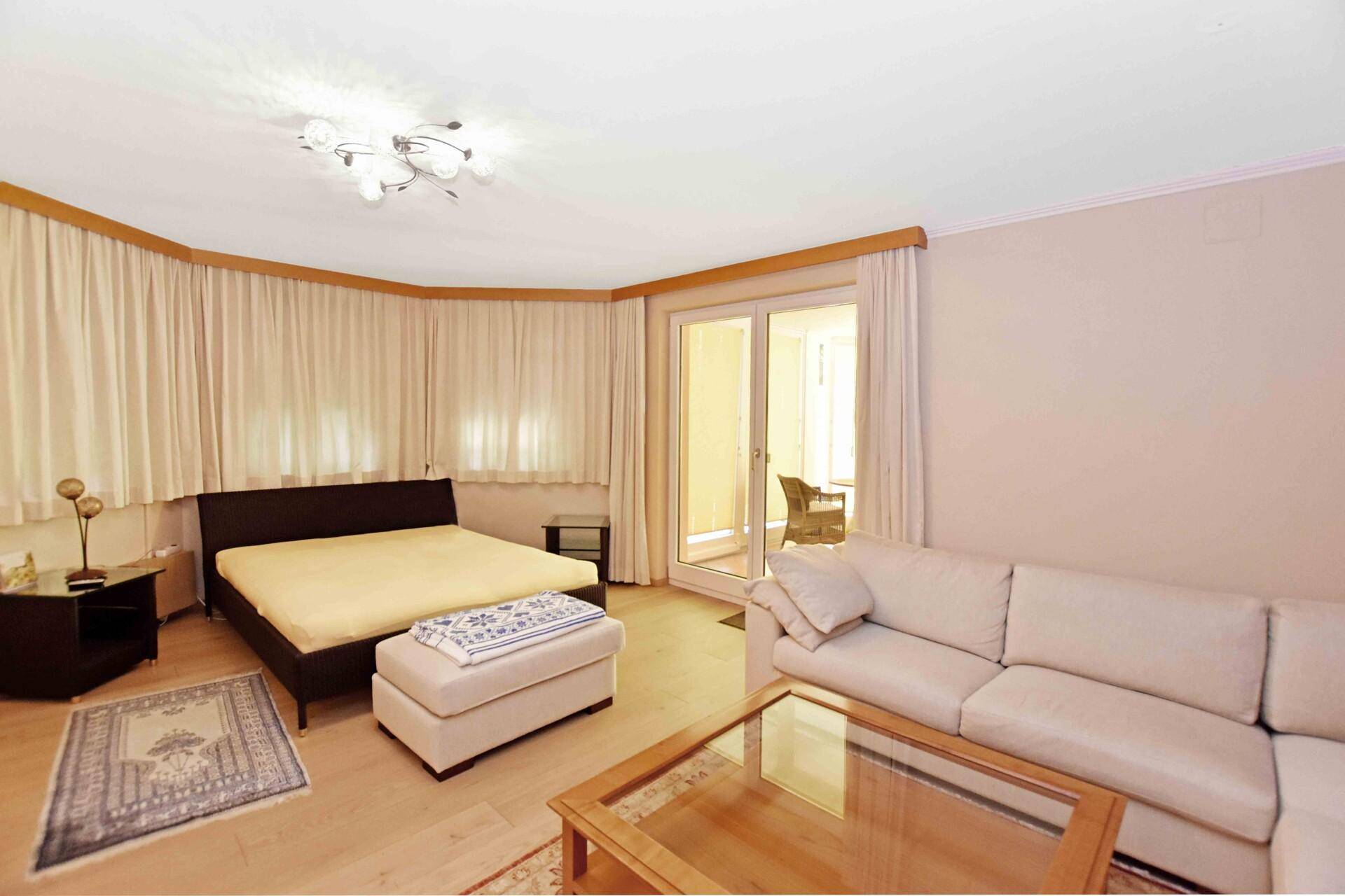 Gemütliches Schlafzimmer mit Doppelbett, Sofa und direktem Zugang zu einem Außenbereich.