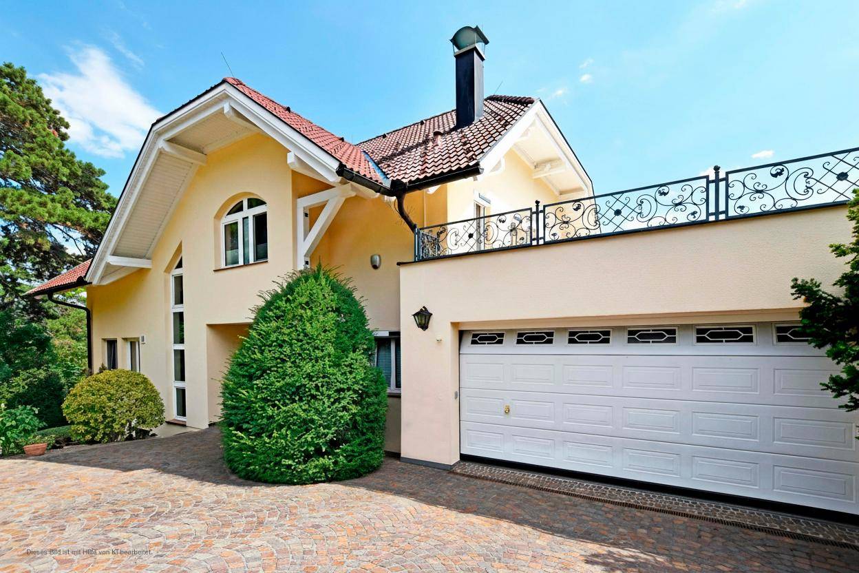 Elegante Hausfassade mit integrierter Doppelgarage und gepflasterter Zufahrt.