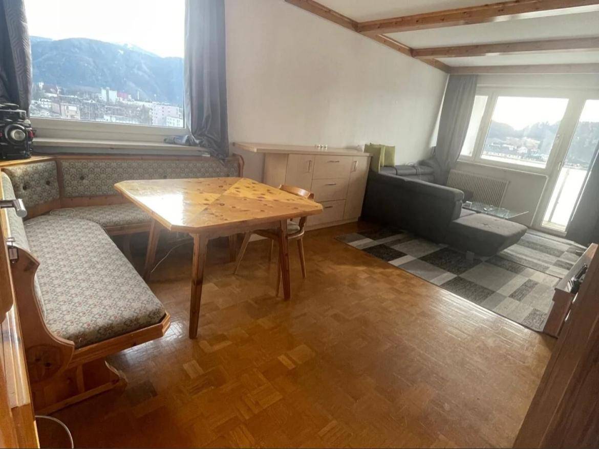 Heller Wohn-Essbereich mit traditioneller Sitzecke, Sofa und weitem Bergblick durch große Fenster.