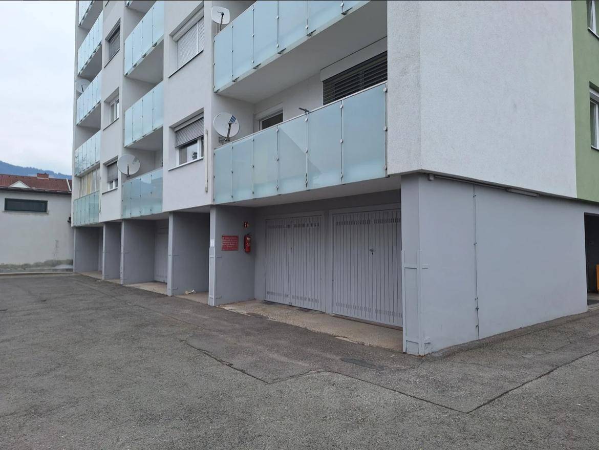 Gebäudefassade mit mehreren Garagenzugängen und darüberliegenden Balkonen.