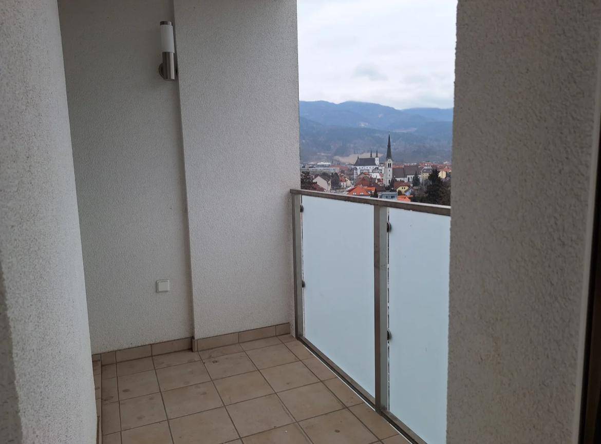 Kleiner Balkon mit Fliesenboden und Blick auf die Stadt und eine historische Kirche.
