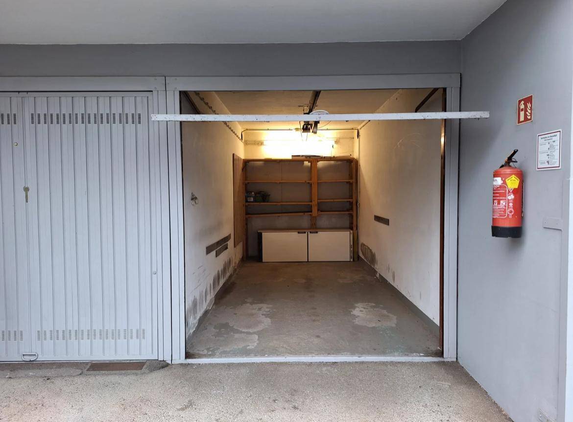 Einzelgarage mit Rolltor und Stauraum an den Wänden.