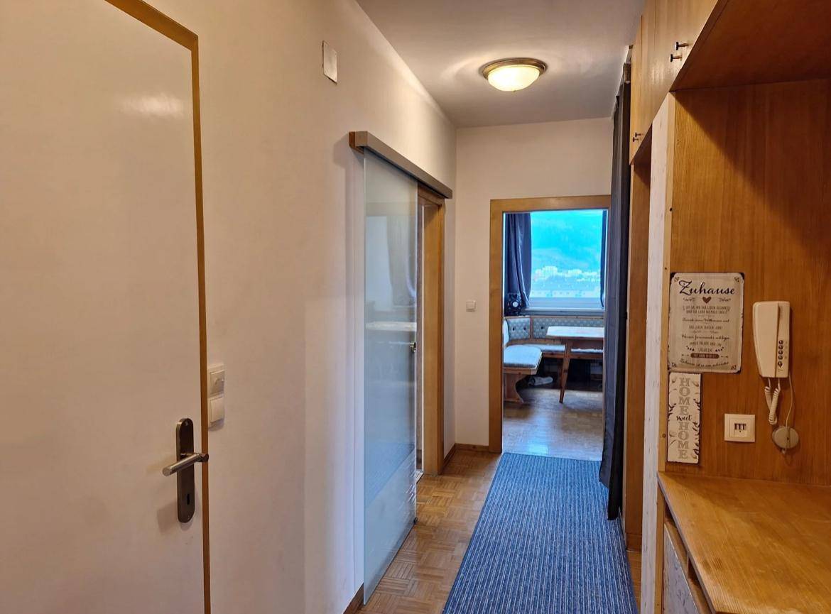 Heller Flur mit Holzschränken, Parkettboden und Blick in den angrenzenden Wohnbereich.