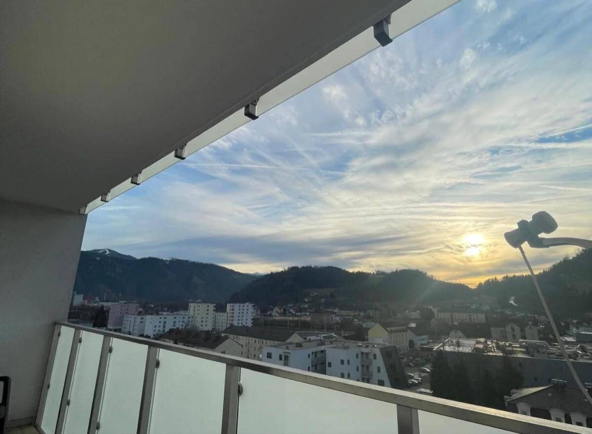 Balkon mit atemberaubendem Blick auf die Berge und die Stadt bei Sonnenuntergang.
