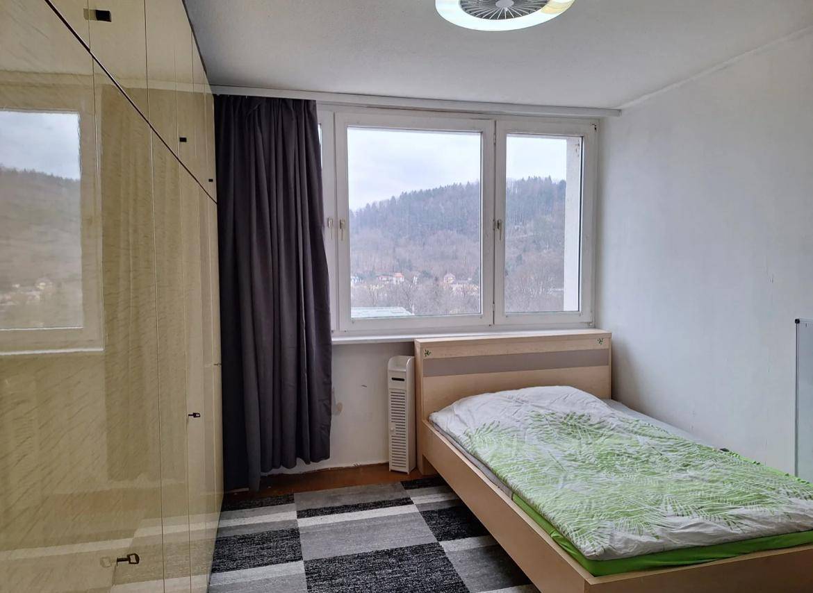 Helles Schlafzimmer mit Einzelbett, großem Kleiderschrank und Ausblick auf grüne Hügel.