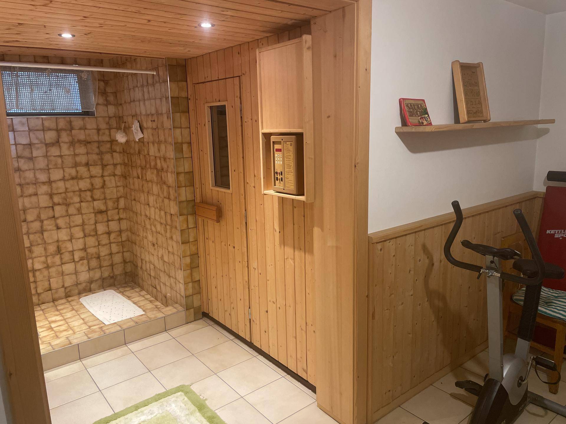 Wellnessbereich im Untergeschoss mit Sauna, Dusche und Fitnessgerät.