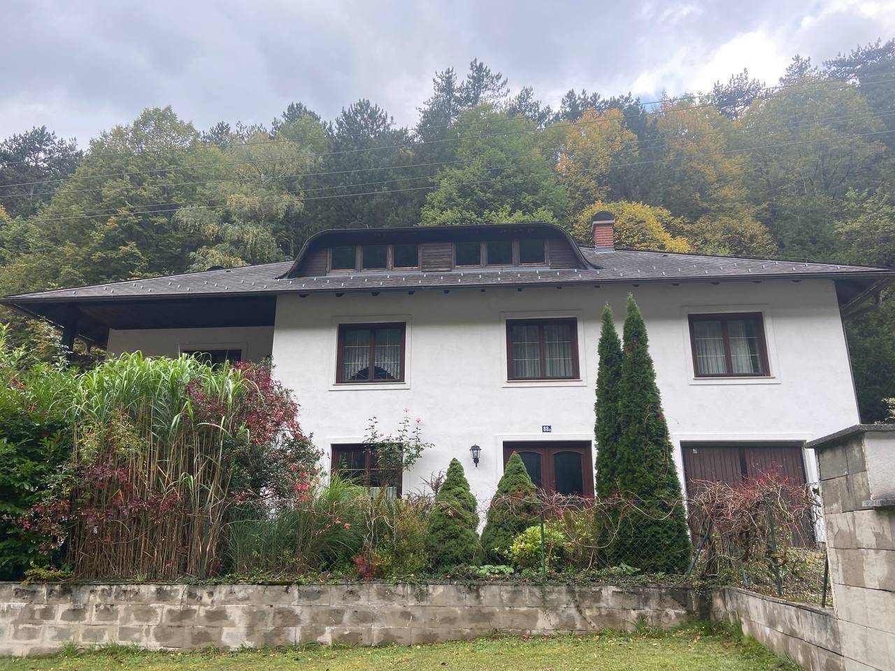 Vorderansicht des Hauses mit gepflegtem Vorgarten und umgebenden Bäumen.