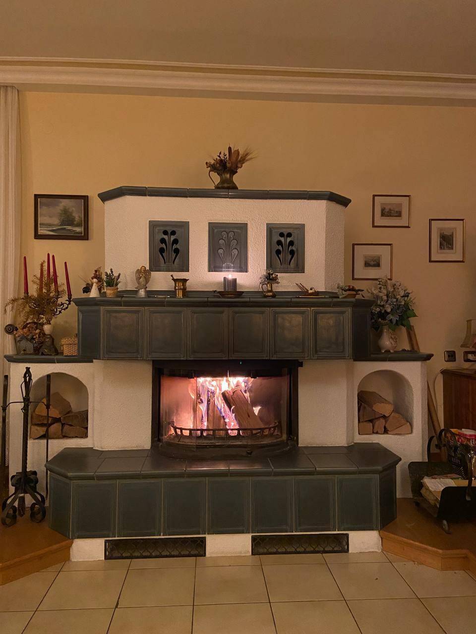 Gemütlicher Wohnbereich mit traditionellem Kachelofen und sichtbarem Feuer.