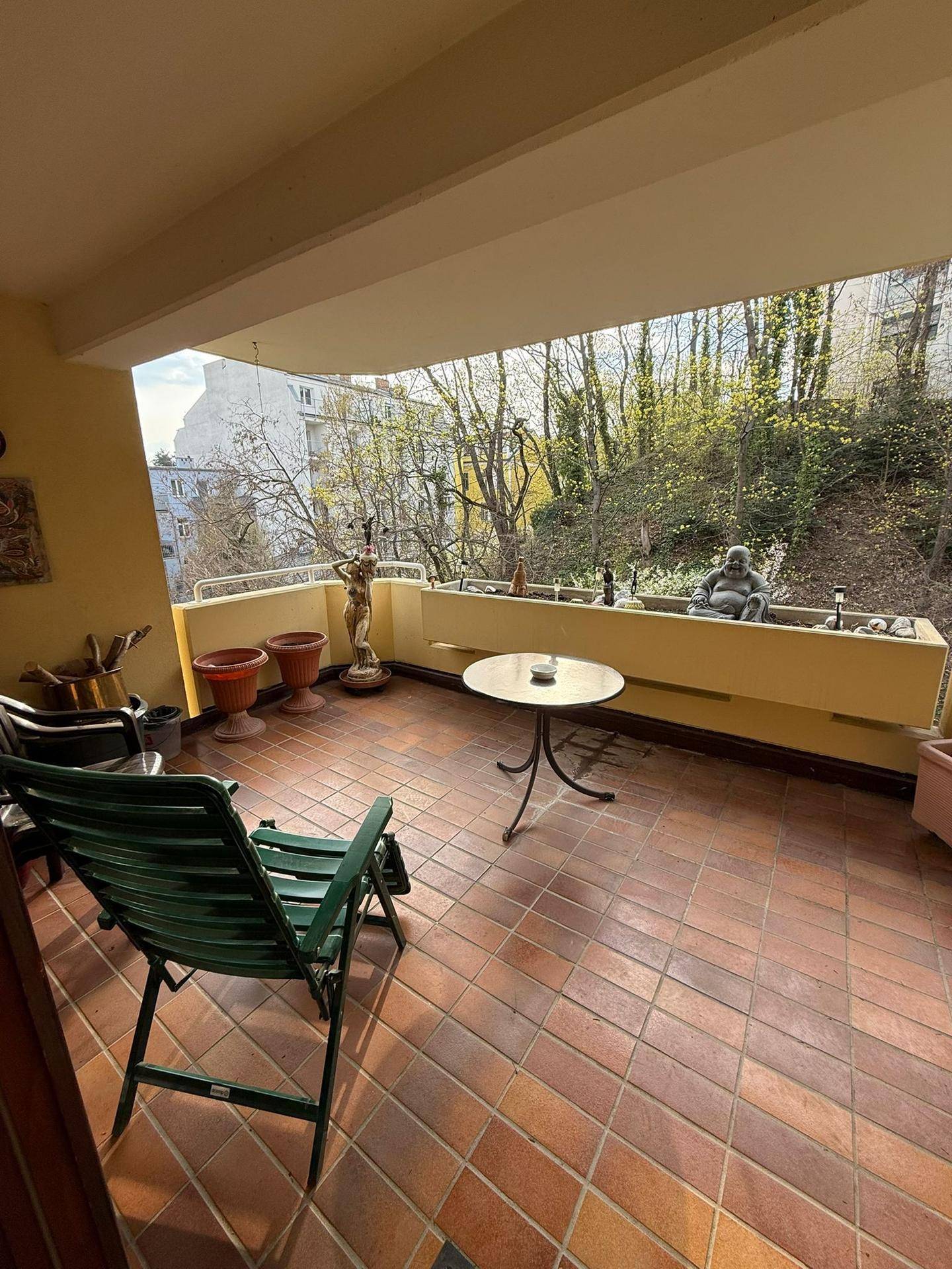 Geräumiger Balkon mit Terrakottafliesen, Sitzgelegenheiten und Blick ins Grüne.