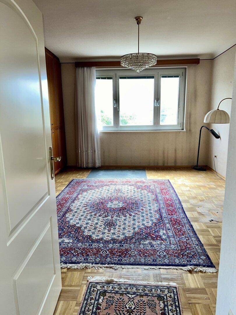 Geräumiges Schlafzimmer mit großem Teppich, Einbauschränken und Kronleuchter.