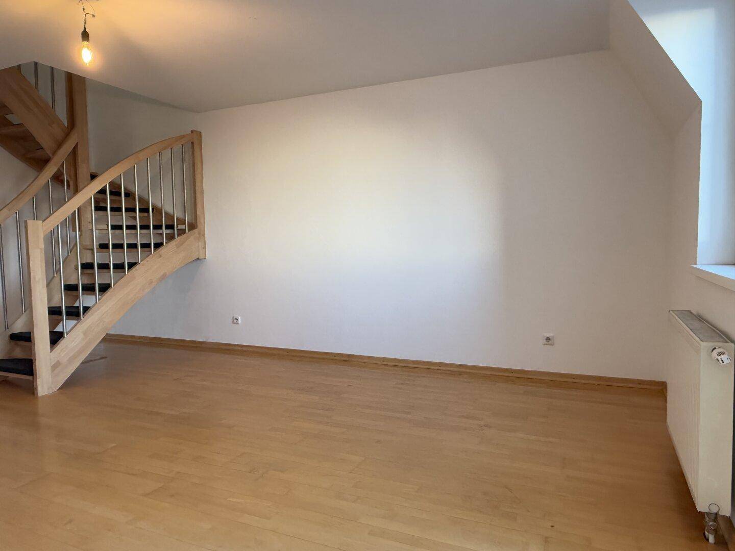 Heller Wohnbereich mit moderner Holztreppe und Parkettboden, bereit zur individuellen Gestaltung.