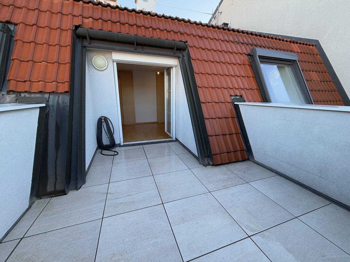 Dachterrasse mit Fliesenboden, Ziegeldach und direktem Zugang zum Innenbereich der Wohnung.