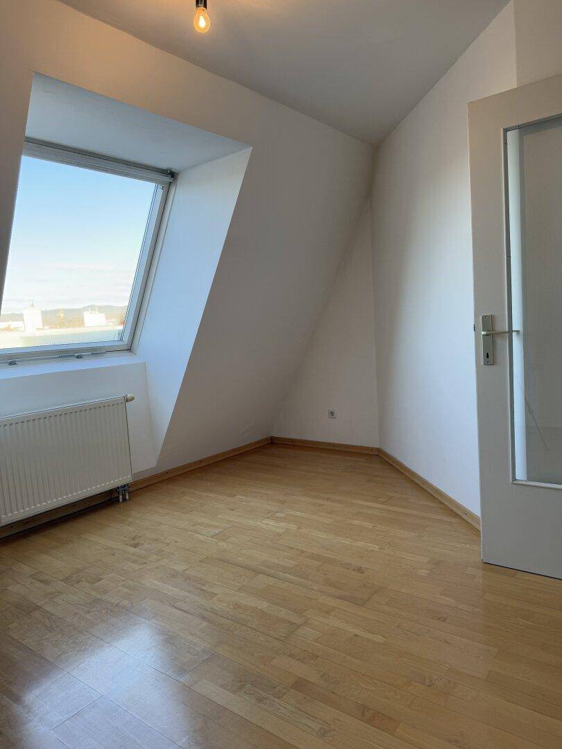 Gemütlicher Raum im Dachgeschoss mit Schrägdecke, Dachfenster und Parkettboden.