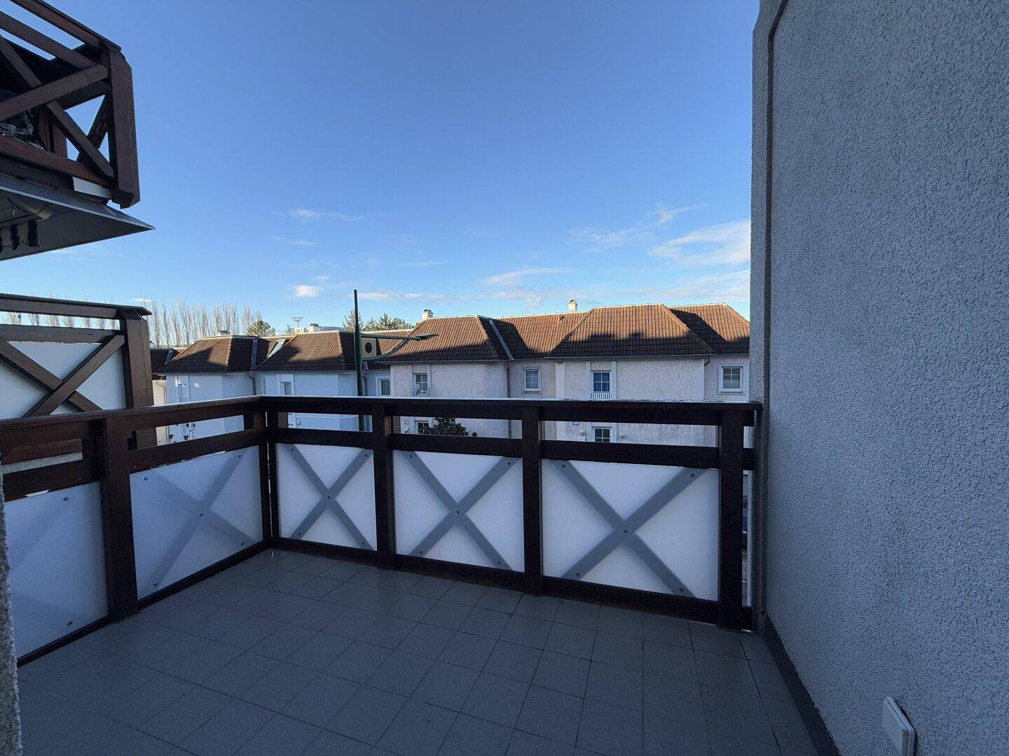 Balkon mit Holzelementen, Fliesenboden und einem weiten Blick auf die Umgebung.