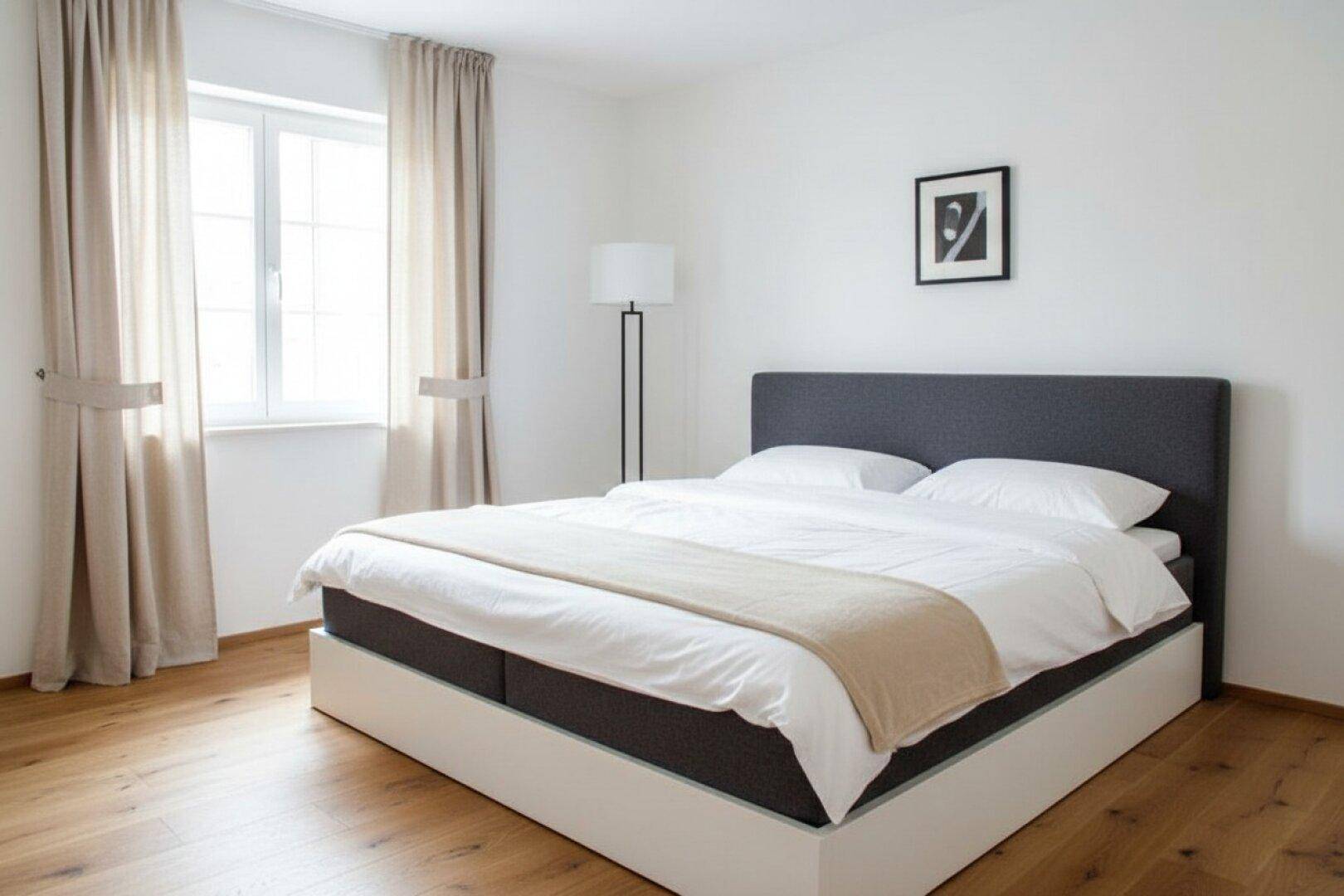 Modernes Schlafzimmer mit Doppelbett, Holzboden und großem Fenster.