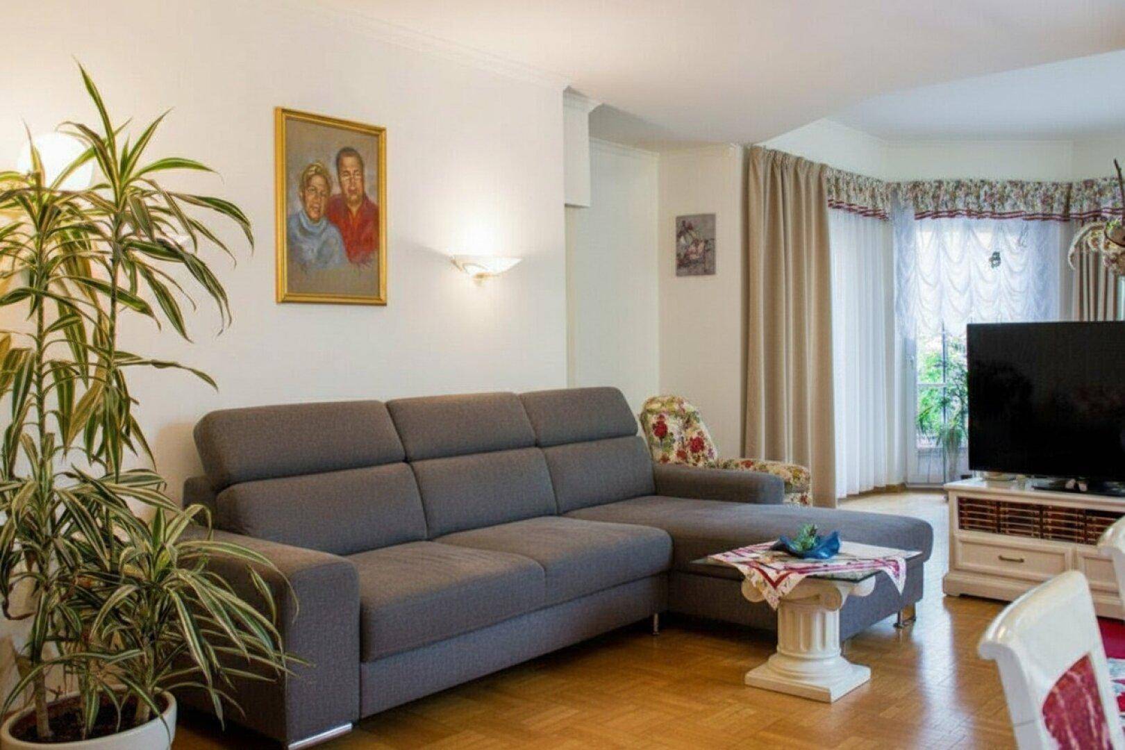 Gemütliches Wohnzimmer mit grauem Sofa, Parkettboden und traditioneller Dekoration.