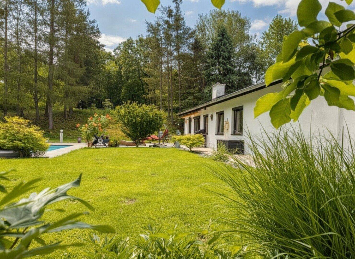 Weitläufiger Garten mit Rasenfläche und Blick auf die weiße Hausfassade.