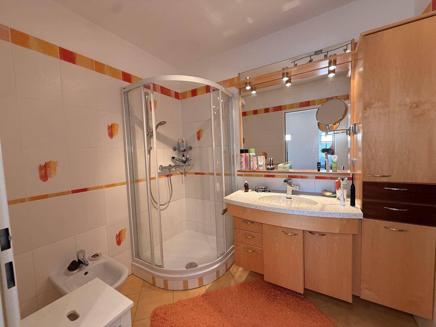 Klassisches Badezimmer mit Duschkabine, Bidet und Waschtisch mit Granitplatte.