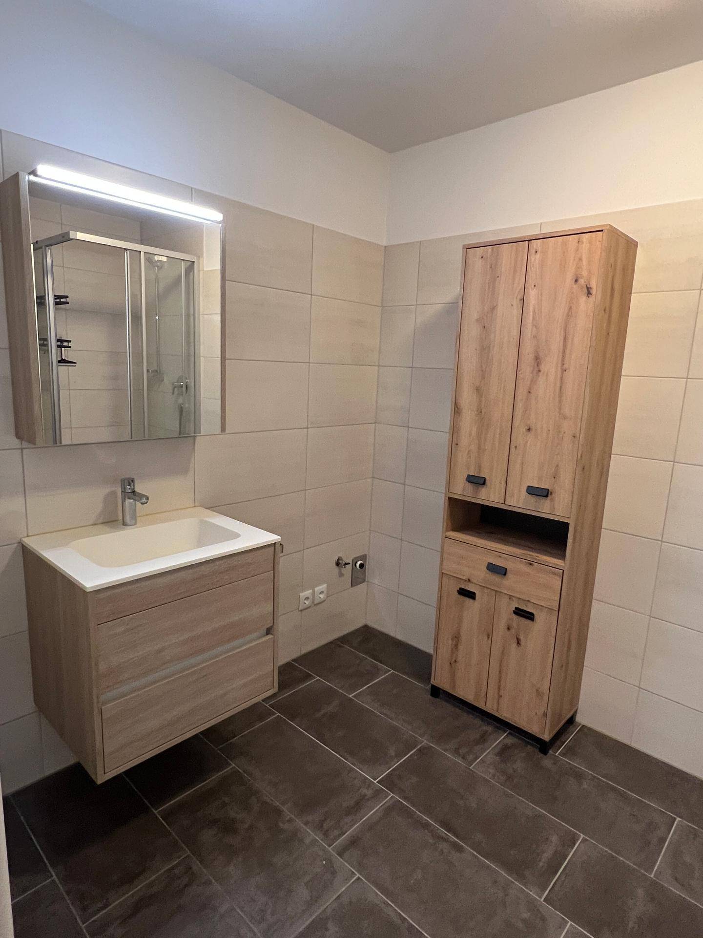 Modernes Badezimmer mit Holzwaschtisch, Spiegelschrank und hellen Fliesen an den Wänden.