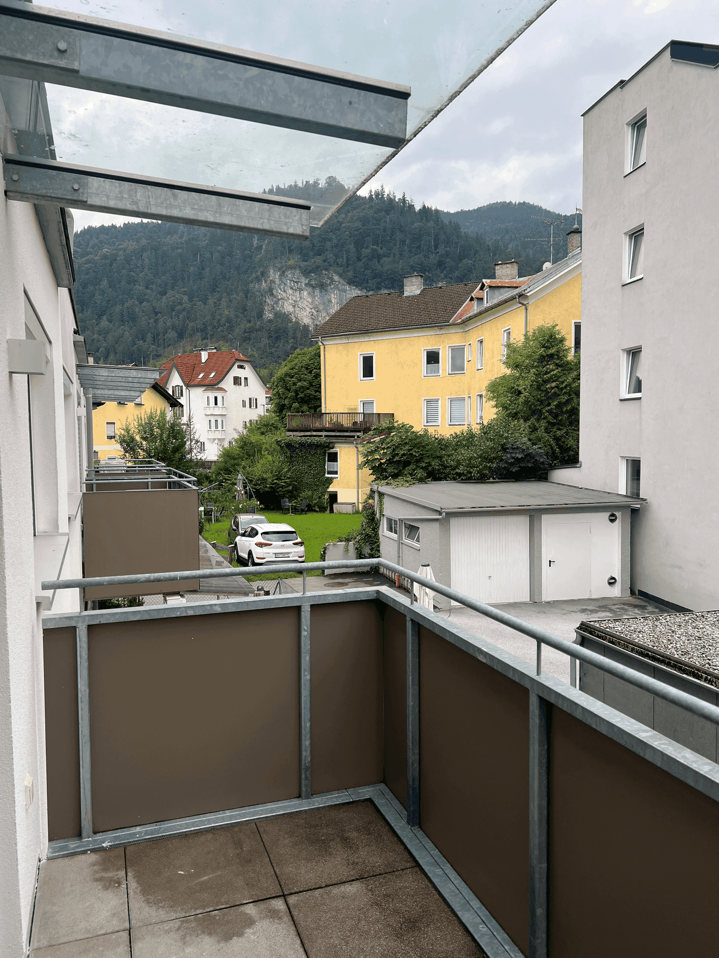 Balkon mit Blick auf die Berge und die umliegende Wohngegend mit viel Grün.