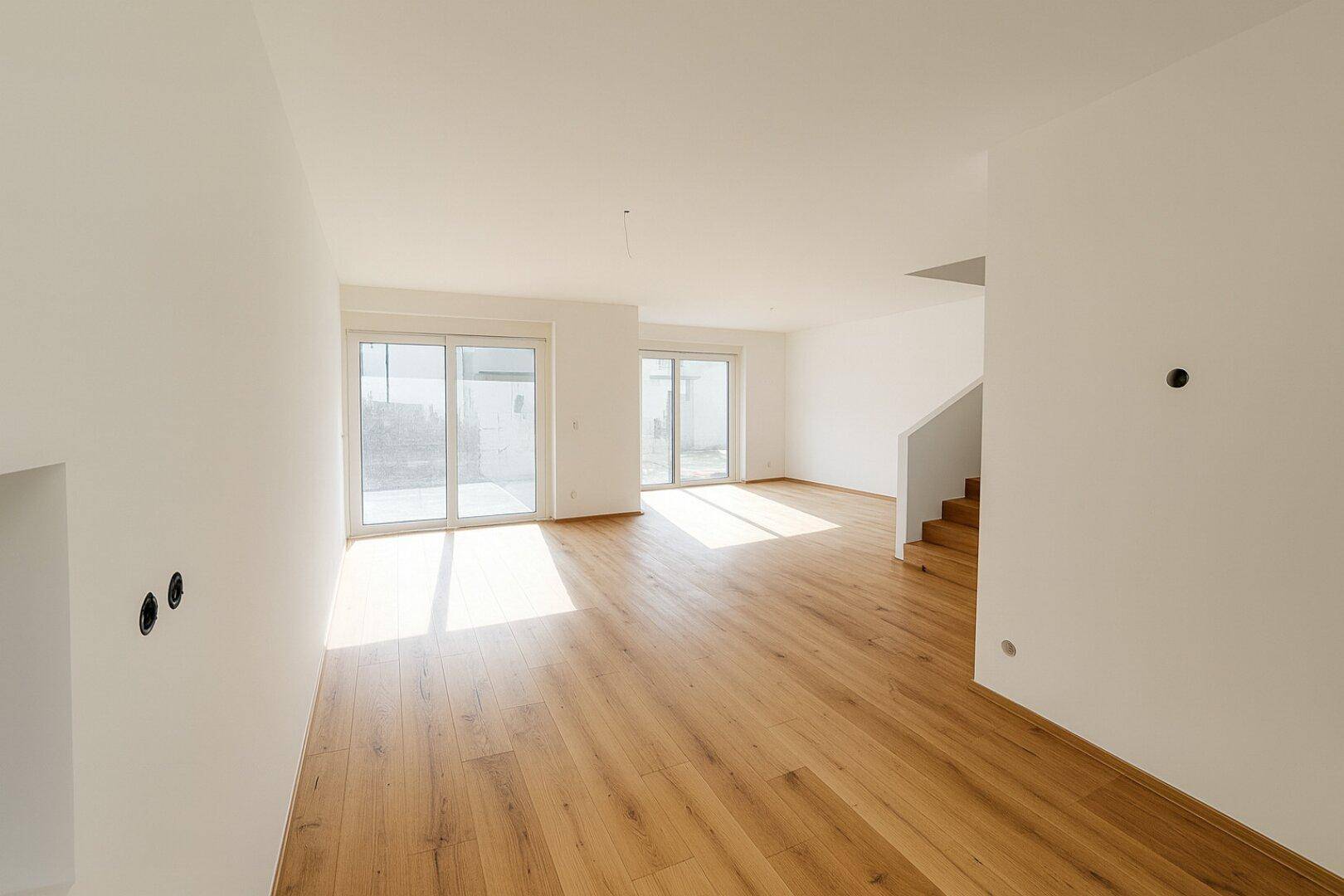 Geräumiger, lichtdurchfluteter Wohnbereich mit Eichenparkett und Zugang zur Terrasse.