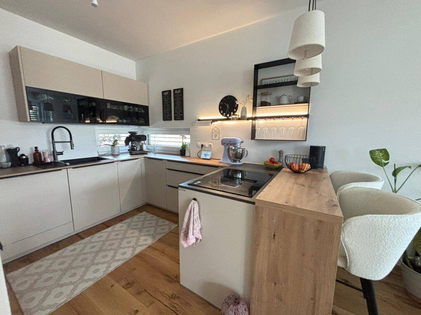 Moderne Einbauküche mit heller Arbeitsplatte, Induktionskochfeld und integriertem Frühstücksbereich.