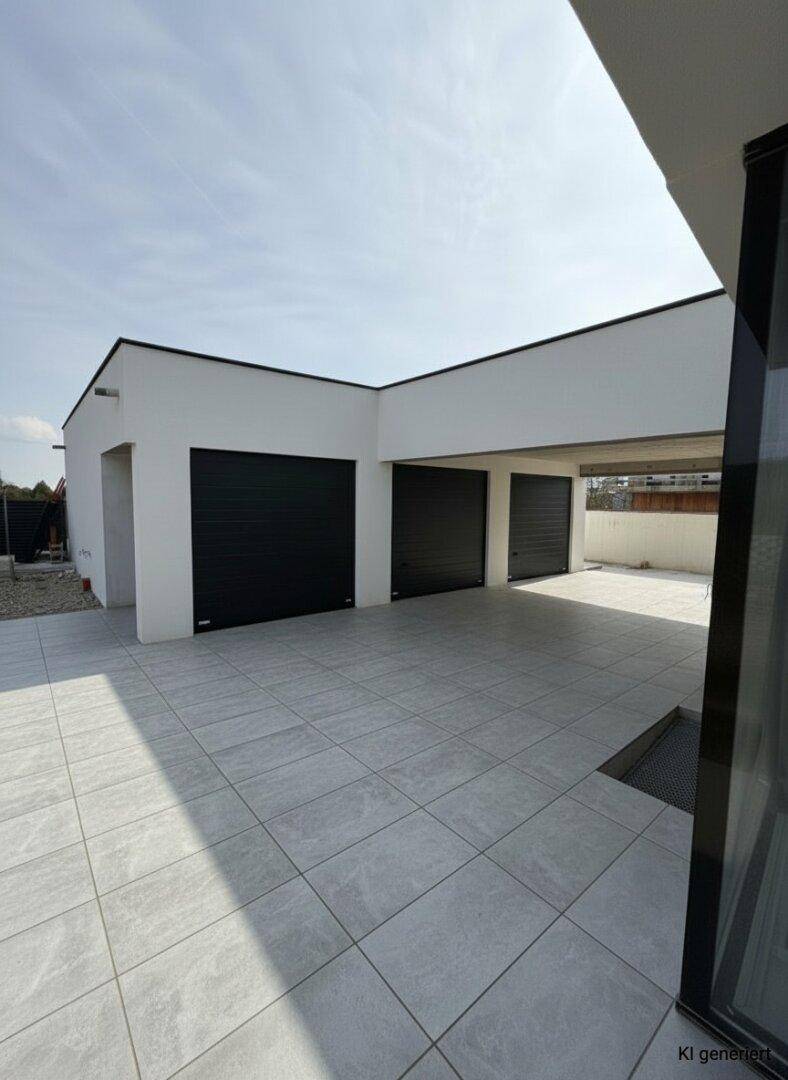 Geräumige Garage mit drei schwarzen Toren und überdachtem Stellplatz auf hellem Fliesenboden.