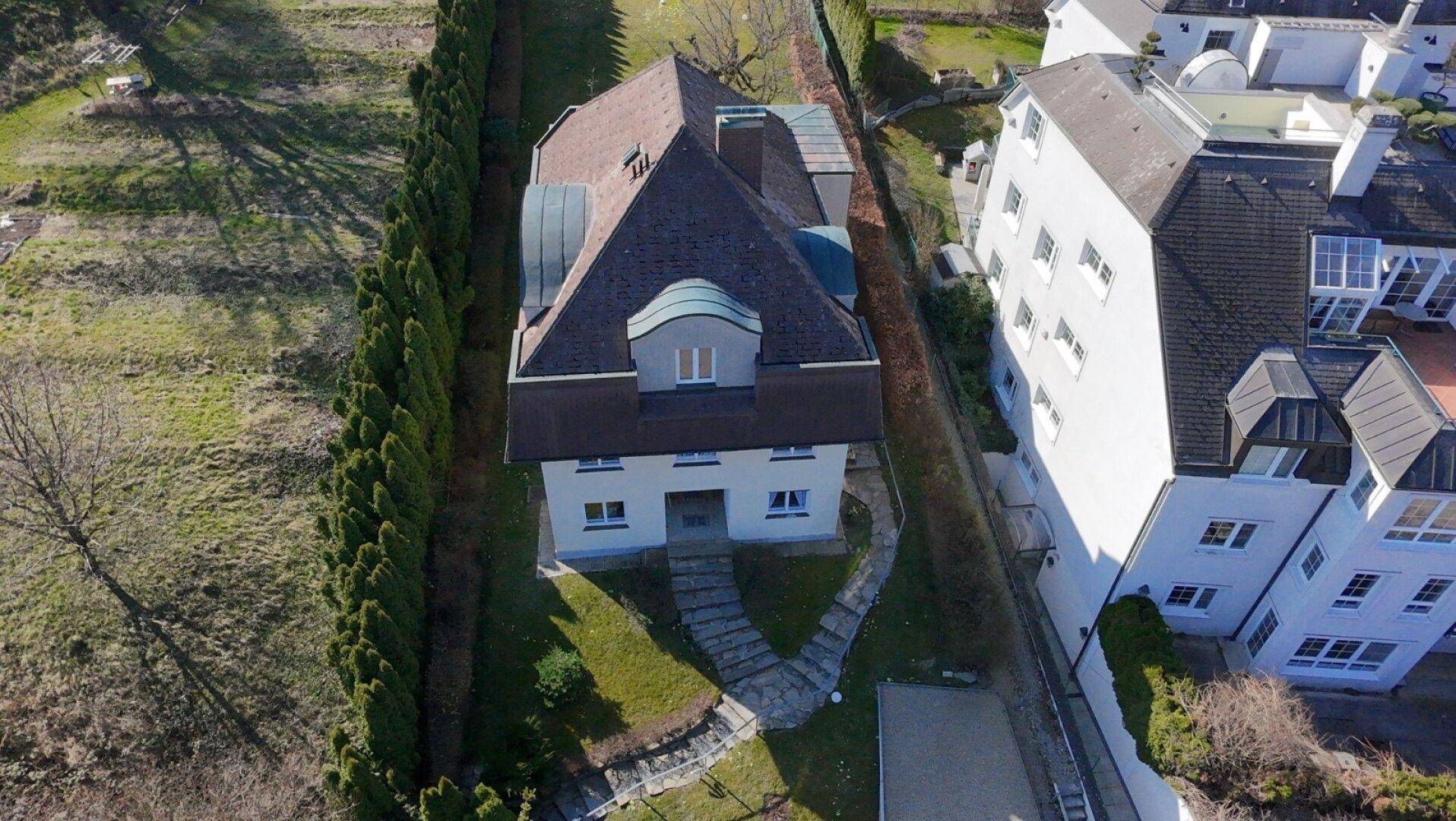 Luftaufnahme des Hauses mit Mansarddach, umgeben von einem langen, schmalen Garten.
