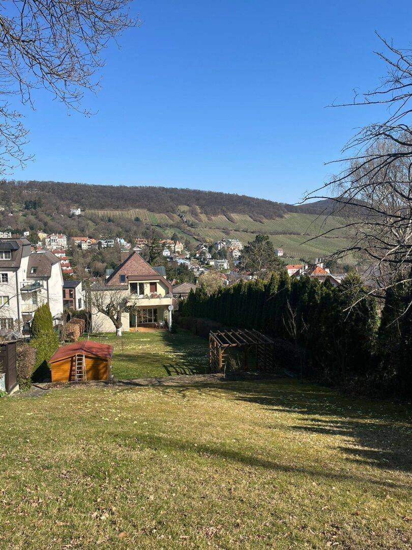 Weitläufiger Garten mit Rasenfläche, Gartenhaus und Blick auf die umliegende Hügellandschaft.