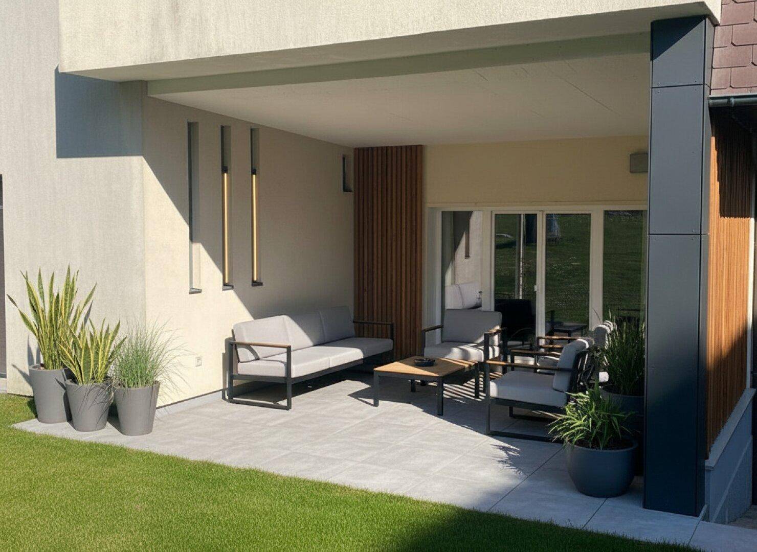 Moderne überdachte Terrasse mit stilvollen Gartenmöbeln und Zugang zum Rasenbereich.