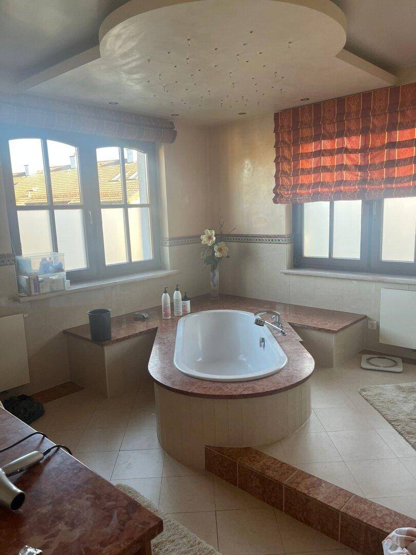 Geräumiges Badezimmer mit eingebauter Badewanne und zwei Fenstern für viel Tageslicht.