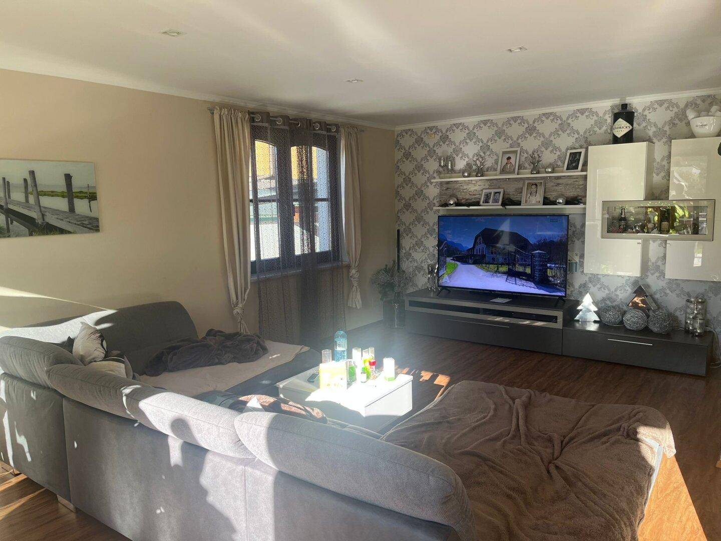 Gemütliches Wohnzimmer mit großem Sofa, Fernseher und dekorativer Tapete.