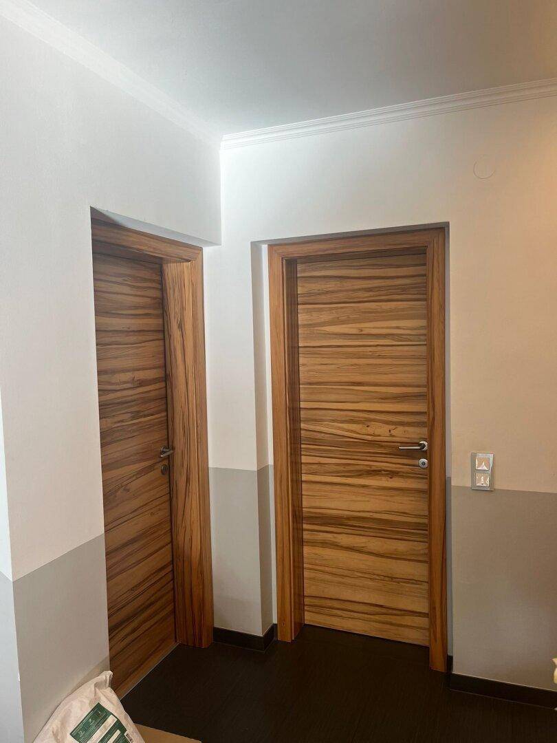 Flur mit zwei modernen Holztüren und zweifarbiger Wandgestaltung.