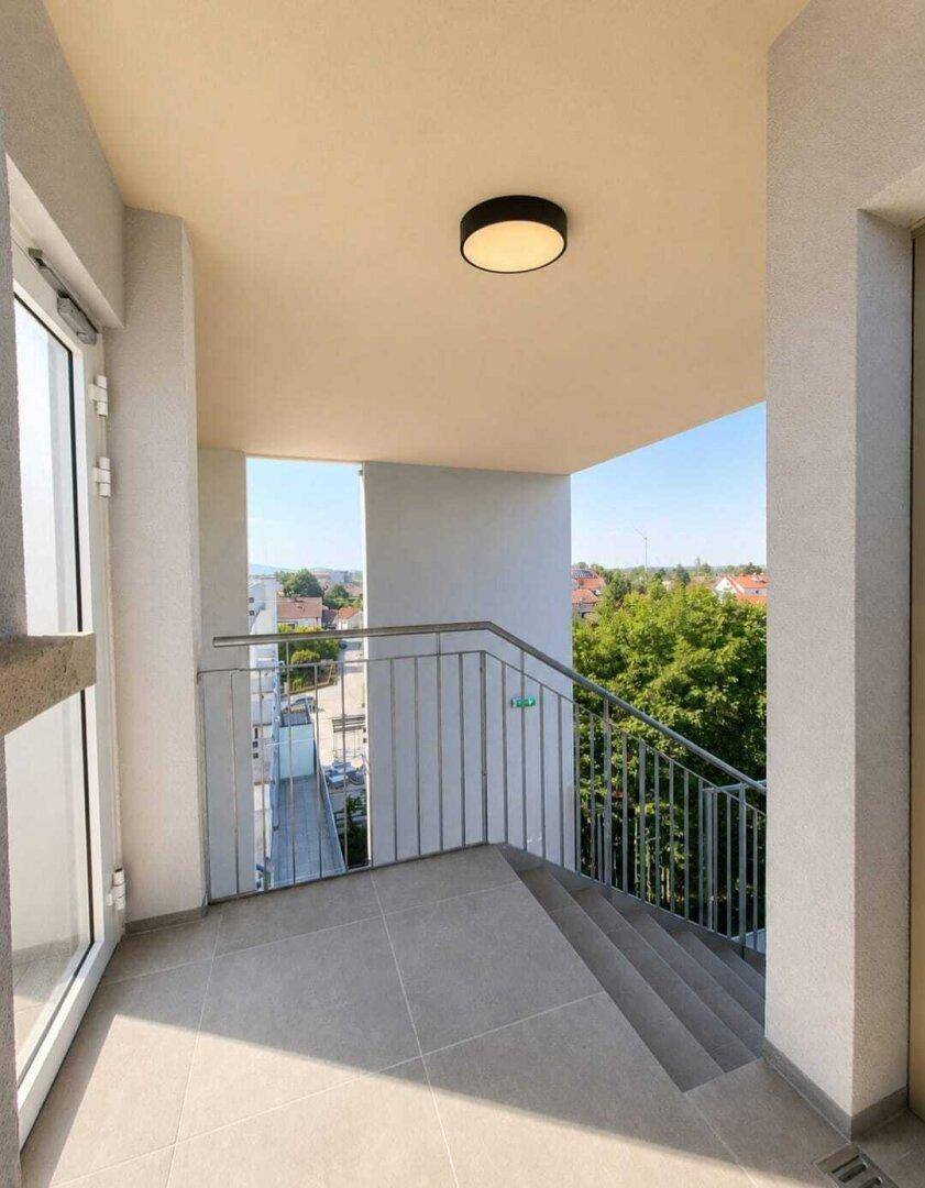 Geräumiger Balkon mit Fliesenboden, Metallgeländer und weitem Blick über die Umgebung.