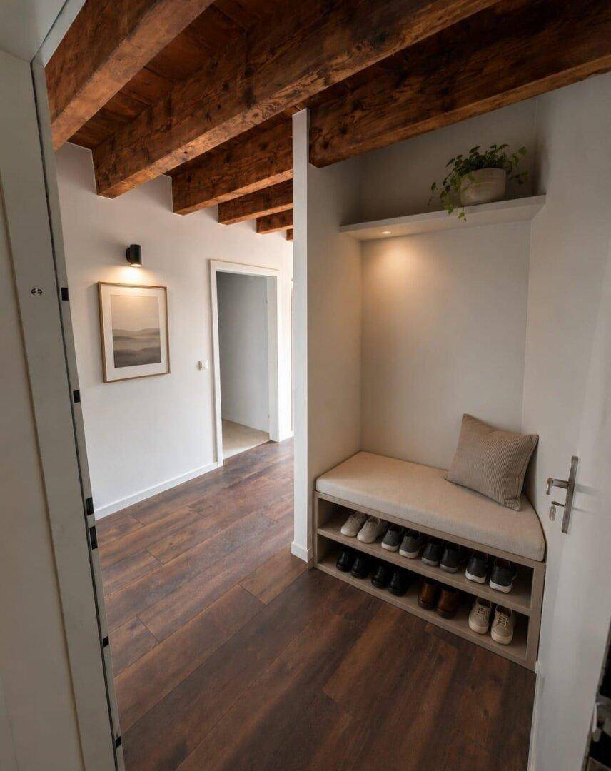 Heller Eingangsbereich mit Holzbalkendecke, dunklem Holzboden und praktischer Schuhbank.