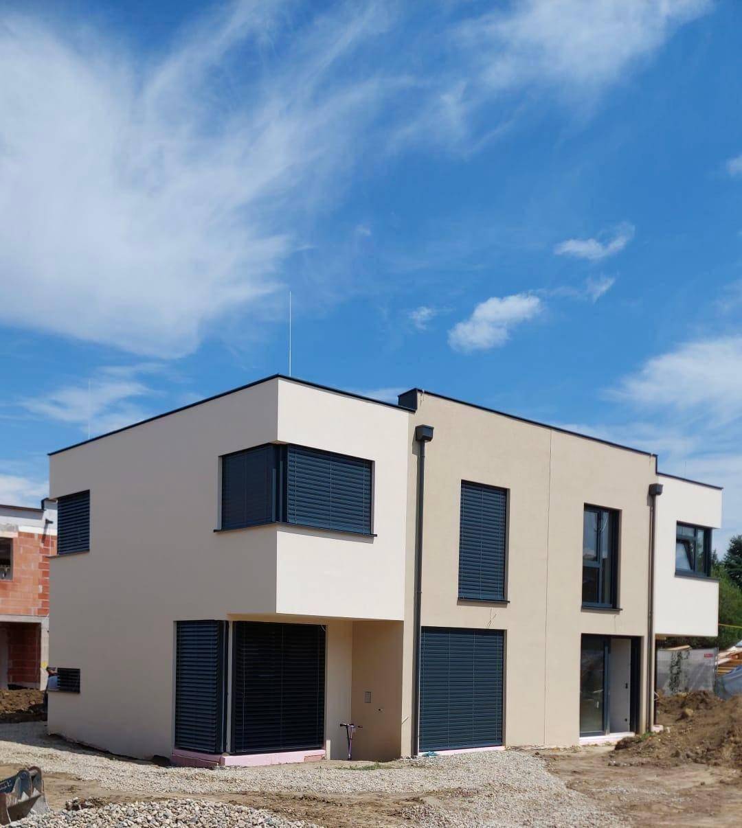 Neubau-Reihenhaus mit modernen Rollläden an den Fenstern und heller Fassade.
