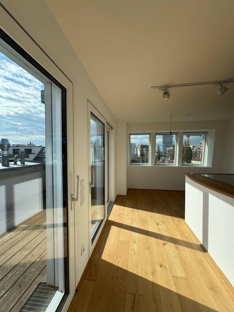 Lichtdurchfluteter Raum mit großen Glasschiebetüren zum Balkon und weitem Stadtblick.