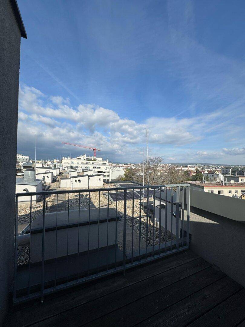 Balkon mit Holzbelag und Metallgeländer bietet einen weiten Blick über die Stadtlandschaft.