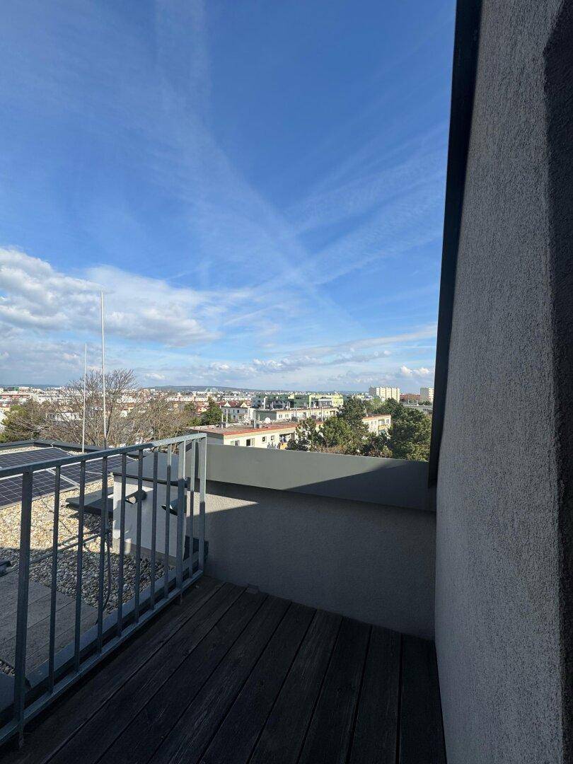 Geräumiger Balkon mit Holzbelag und Metallgeländer, ideal für entspannte Stunden mit Stadtblick.