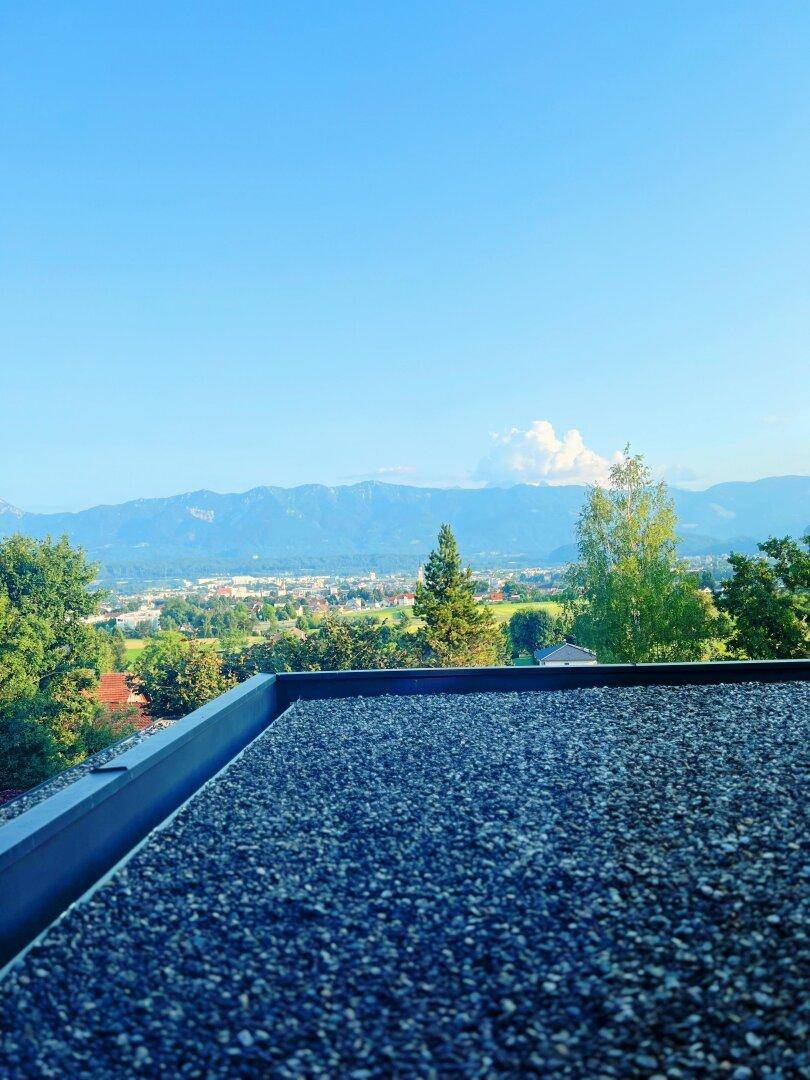 Flachdach mit Kiesbelag und weitem Panoramablick auf die Stadt und die Berge.